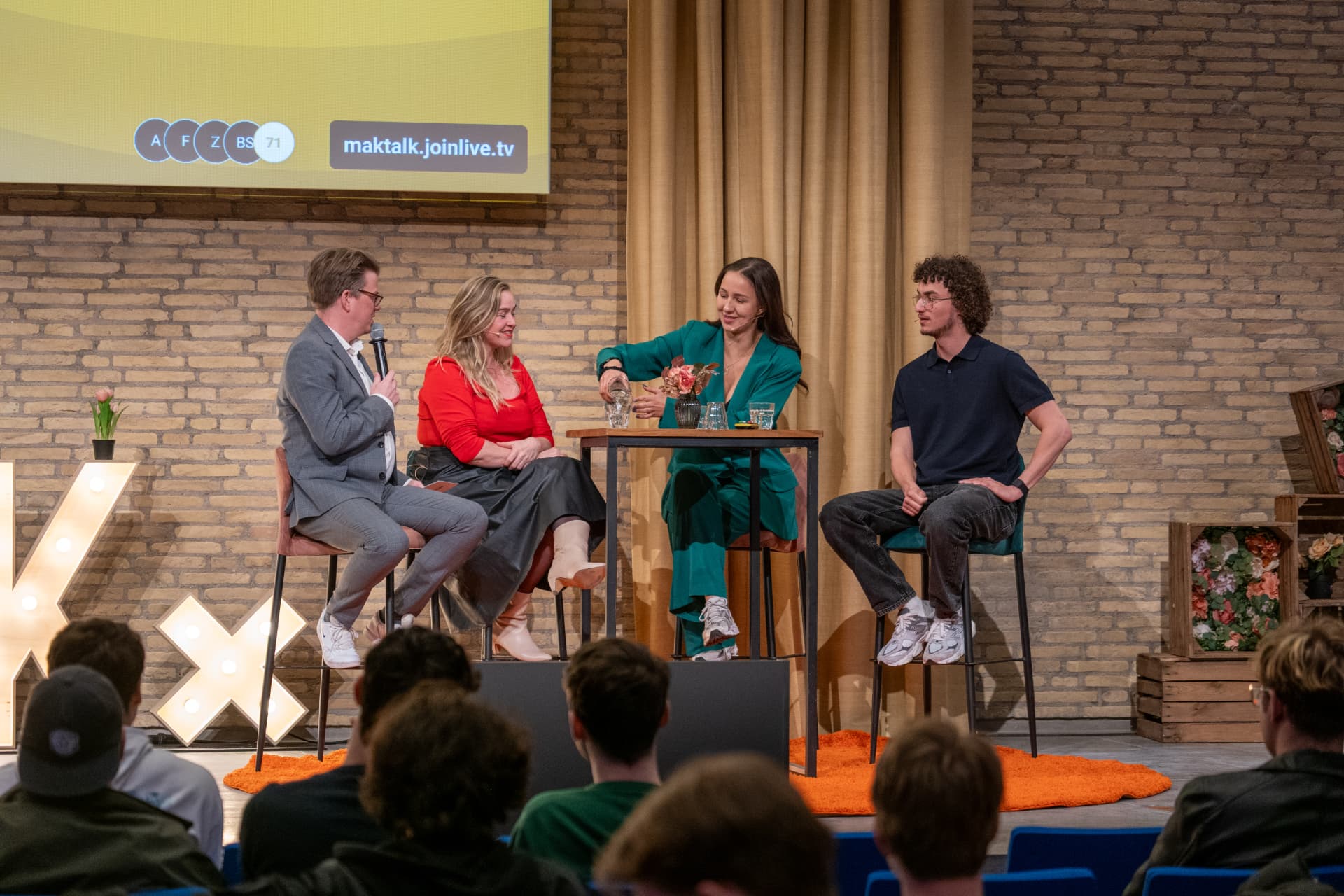 Jerre Maas modereert een panelgesprek met drie gasten aan een statafel tijdens MAKtalk