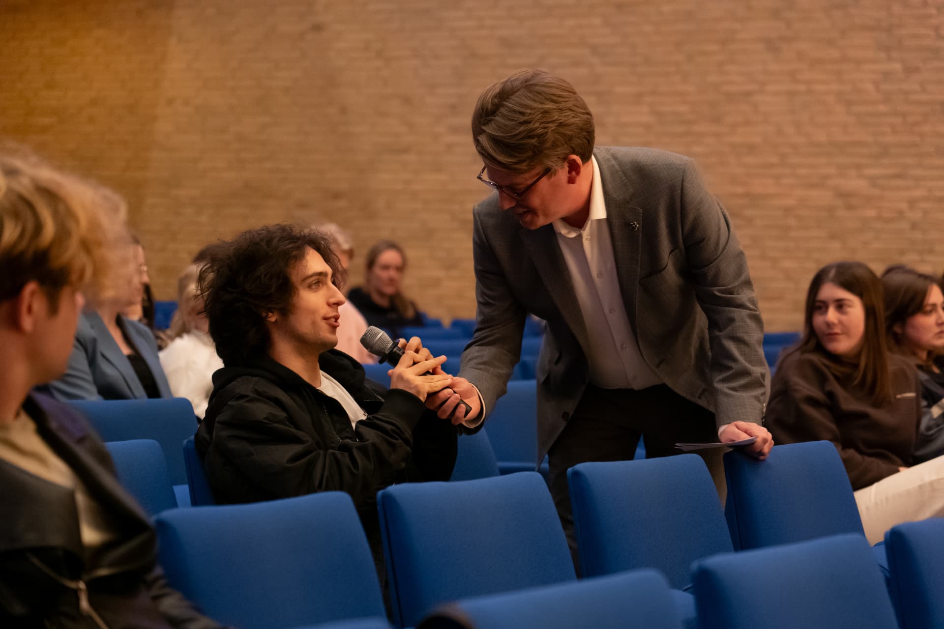Jerre Maas in gesprek met een student in de zaal, oog in oog