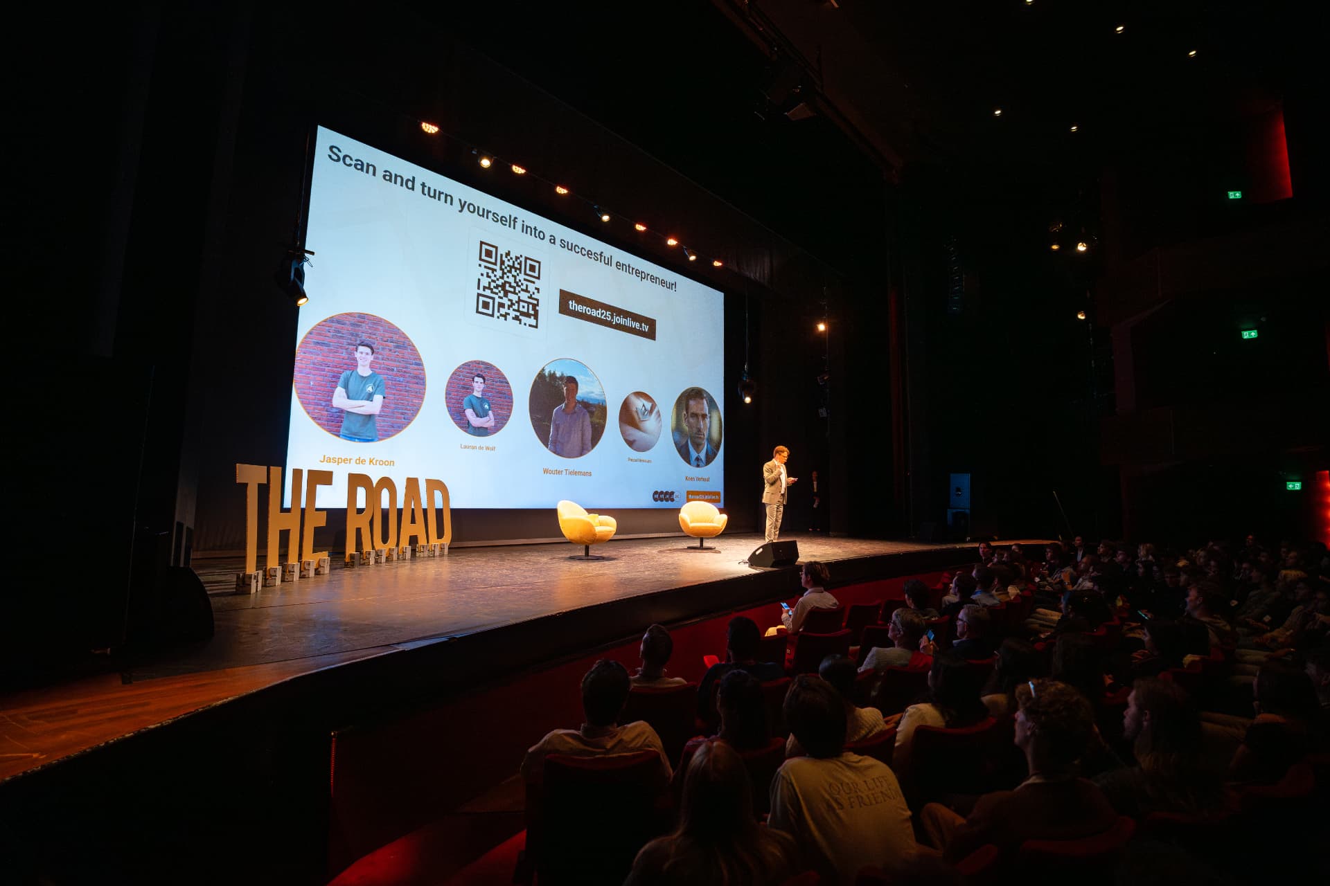 Jerre Maas als dagvoorzitter voor een volle theaterzaal bij symposium The Road